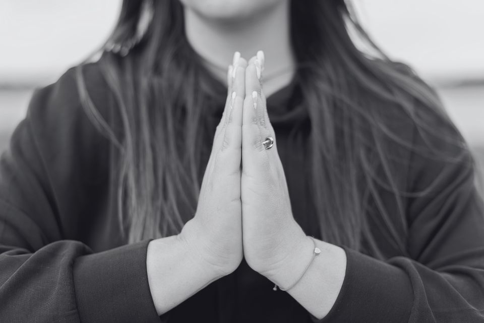 A black and white photo of a woman holding her hands in prayer, in front of her chest.