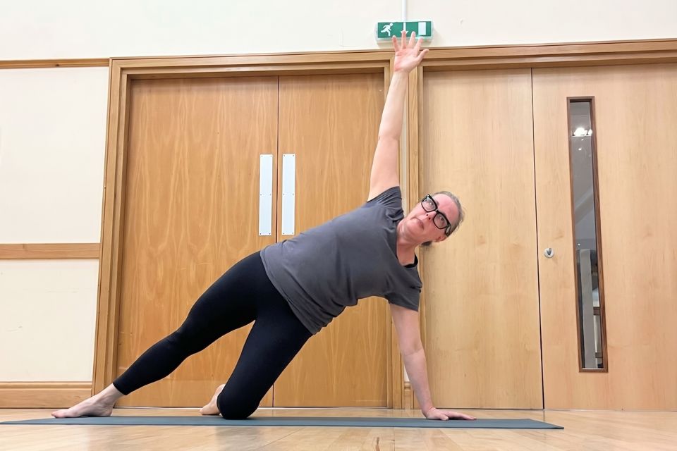 Jayne, founder of Ad Astra Yoga and Pilates, in a side plank position, demonstrating one of the Pilates moves for strength.
